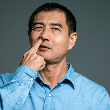 man in blue top picking nose